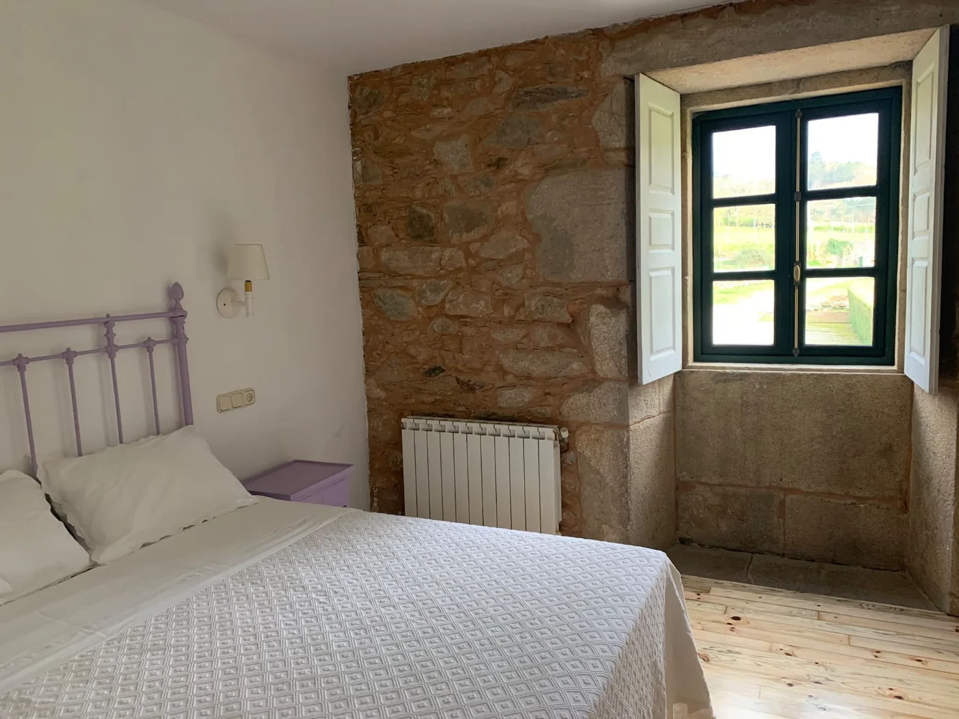 Habitación con pared de piedra y ventana al campo